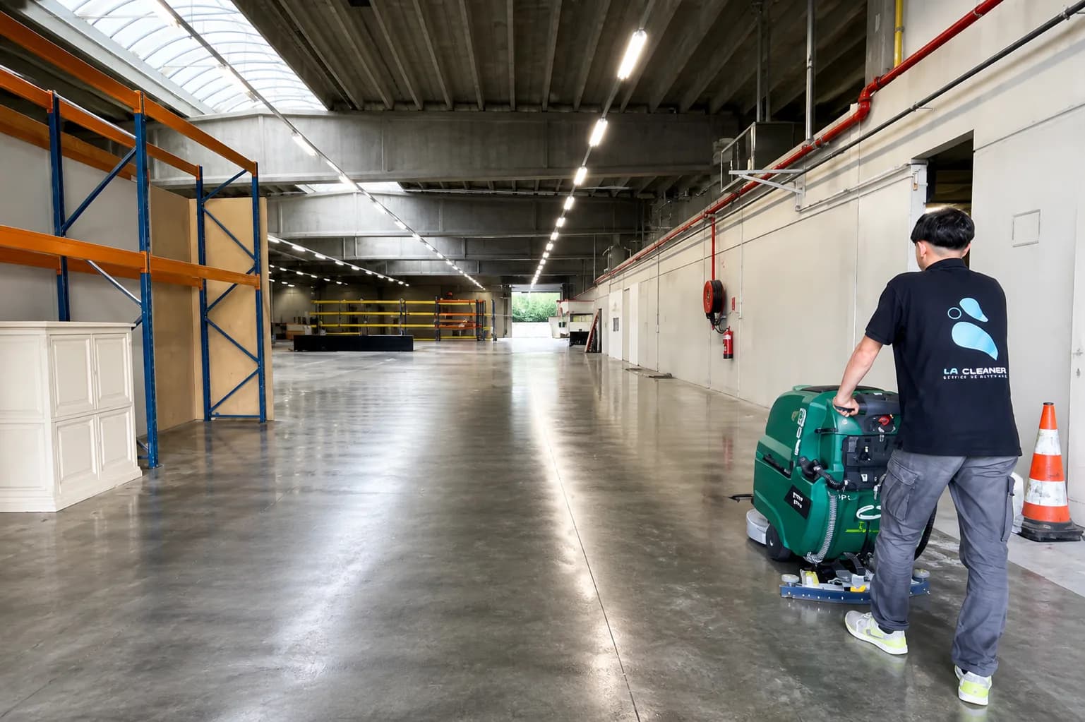 Agent LF Cleaning conduisant une autolaveuse dans un entrepôt